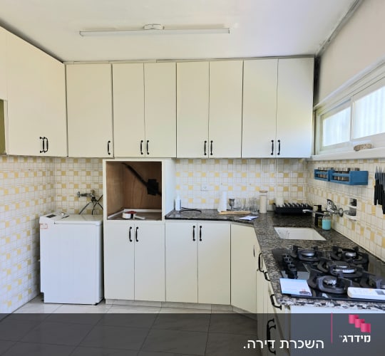 מטבח עם ארונות לבנים וכיריים גז